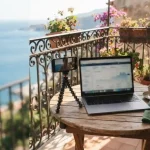 Phone on a selfie tripod and laptop on a seaside balcony, illustrating the AzurSlot review