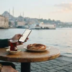 Phone chat and a glass of tea at a waterfront cafe, reflecting the Lukkly Casino review