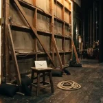 Bare timber back of a lit theatre set with an envelope on a stool, illustrating the LunuBet review