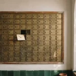 Brass post office boxes with one open holding an envelope, echoing the Miami Club review